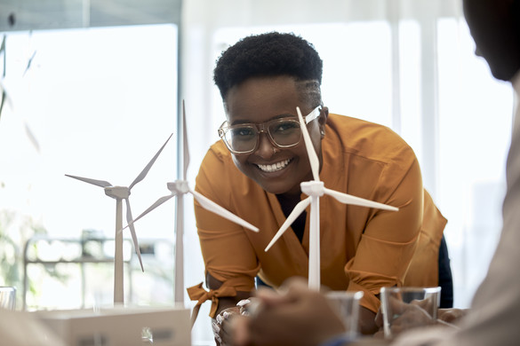 smiling employee behind a model of a wind farm