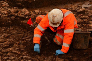Person wearing PPE and hard hat digging for archaeological finds along the National Grid Hinkley Connection route