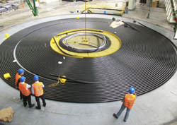 People wearing hard hats and high-vis jackets looking at high-voltage sub-sea cable coiled on the floor