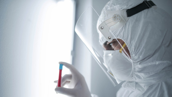 Person wearing full PPE holding blood vial used for National Grid 'Backing the quest for a COVID-19 vaccine' story