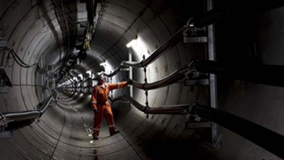 Engineer wearing orange overalls and a hard hat standing inside National Grid's London Power Tunnel